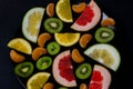 Shredded bright vivid brilliant yellow green orange red grapefruit lemon orange Mandarin kiwi sweetie in a black plate on black ba Royalty Free Stock Photo