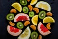 Shredded bright vivid brilliant yellow green orange red grapefruit lemon orange Mandarin kiwi sweetie in a black plate on black Royalty Free Stock Photo