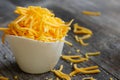 Shredded cheddar cheese in white cup close up view