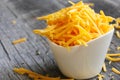 Shredded cheddar cheese in white cup close up view