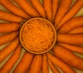 Shredded fresh carrots in a bowl with whole carrots around. Top view. Fresh carrot for backgrounds or textures