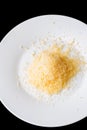 Shredded grated cheese in a large white ceramic plate on a black Royalty Free Stock Photo