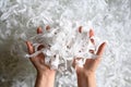 Shredded paper heap in hands, top view of many white strips