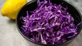 Shredded red cabbage with lemon in black bowl on grey background. Vegetarian healthy food. Top view