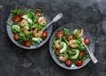 Shrimp, arugula,avocado, cherry tomatoes salad served on two plates on a dark background, top view Royalty Free Stock Photo