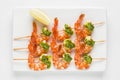 Shrimp kebab served with sauce and lemon top view on a white background. Prawn starter on skewers top view