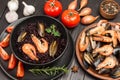 Shrimp and mussels with black rice in bowl. Tomatoes, onions and garlic on table. Mussels and shrimps in plate