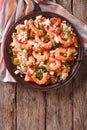 Shrimp saganaki with tomato and feta cheese on a plate. vertical