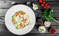 Shrimp salad with parmesan cheese, croutons, tomatoes, mixed greens, lettuce on wooden background.