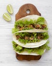 Shrimp tacos on wooden board on white wooden surface, top view. Mexican cuisine. Flat lay, from above, overhead