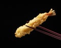 Shrimp tempura lifted with chopsticks against a black background Royalty Free Stock Photo