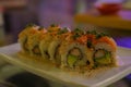 shrimp tempura roll with avocado topped with salmon, sesame seeds, and green onion at restaurant Royalty Free Stock Photo