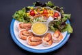 Shrimpand salad of fresh vegetables close-up on a plate on black background. horizontal view from above