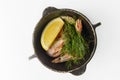 Shrimps with dill and slice of lemon served in a small black pot over white background. Royalty Free Stock Photo