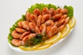 Shrimps in red spicy sauce, beautifully laid out in a plate, lemon slices and greens lie next to them