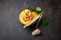 Shrimps Tom Yam Kung in grey bowl with thai spices on autentic tray top view, wooden background