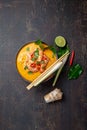 Shrimps Tom Yam Kung in grey bowl with thai spices on autentic tray top view, wooden background