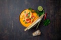 Shrimps Tom Yam Kung in grey bowl with thai spices on autentic tray top view, wooden background