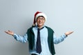 Shrugging Man Smiling Studio. Guy in Santa Claus Hat Standing Raising Hands Royalty Free Stock Photo