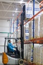 SHUCHIN, BELARUS - JANUARY 26, 2015. Worker driver of a forklift loader at warehouse with cardboard boxes on pallet