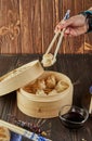 Shumai shaomai Chinese meat dumplings steamed in a bamboo steamer. Hand with chopsticks holding dim sum Royalty Free Stock Photo