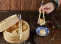 Shumai shaomai Chinese meat dumplings steamed in a bamboo steamer. Hand with chopsticks holding dim sum Royalty Free Stock Photo