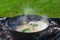 Shurpa soup in a large cast-iron cauldron outdoor. Summer food for hike. Royalty Free Stock Photo