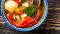 Shurpa soup in plate with oriental ornament, wooden background. Top view. traditional Asian, Uzbek, Middle East soup with beef or