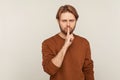 Shut up, be quiet! Portrait of mystery man with beard wearing sweatshirt showing silence gesture with finger on lips