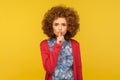 Shut up, don`t speak! Portrait of displeased woman with curly hair shushing, holding finger on lips