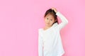 Shy asian little girl make gesture scratching head isolated on pink background with copy space Royalty Free Stock Photo