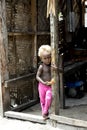 Shy blond baby girl with dark skin in handmade house, Solomon Islands
