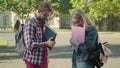 Shy boy and girl in eyeglasses standing in university campus yard and talking. Side view portrait of Caucasian nerds