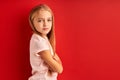 Shy confident caucasian child girl isolated over red studio background Royalty Free Stock Photo
