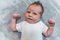 Shy facial expression. Adorable caucasian newborn baby boy in white t-shirt looking bashfully at camera and clenching Royalty Free Stock Photo