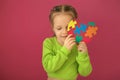 A shy girl hides her face behind cardboard heart made of multicolored puzzles Royalty Free Stock Photo