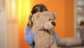 Shy girl hiding behind plush toy, preschooler feeling lonely and hopeless