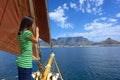 Shy girl on yacht with red sails looks at waves