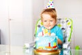 Shy happy toddler blow candles on birthday cake