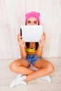 Shy hipster girl hiding her face behind tablet Royalty Free Stock Photo