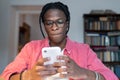 Shy introverted African American man chatting on phone flirting with girl via internet sits at table