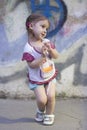 Shy kid girl with pigtails on a background of a concrete wall with graffiti Royalty Free Stock Photo