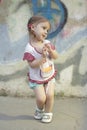 Shy kid girl with pigtails on a background of a concrete wall with graffiti Royalty Free Stock Photo