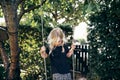 Little blonde girl playing on a tree swing outside Royalty Free Stock Photo