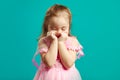 Shy little girl covers her face with hands on blue isolated background. Royalty Free Stock Photo