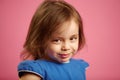 Shy little girl with cute look, close-up portrait on pink isolated background. Royalty Free Stock Photo