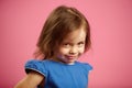 Shy little girl with cute look, portrait on pink isolated background.