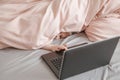 Shy scared girl lying in bed under blanket and learning in virtual online school class. Kid working on laptop Internet at home. Royalty Free Stock Photo