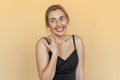 Shy, timid, pretty young woman with freckles stands over beige background. Beautiful girl surprised and wondered looks aside. Royalty Free Stock Photo