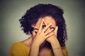 Shy woman hiding face timid. Woman peeking though hands. Gray background.